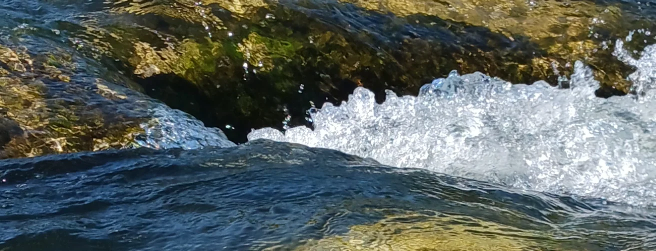 Wasser strömt sprudelnd zwischen Felsen in der Sonne